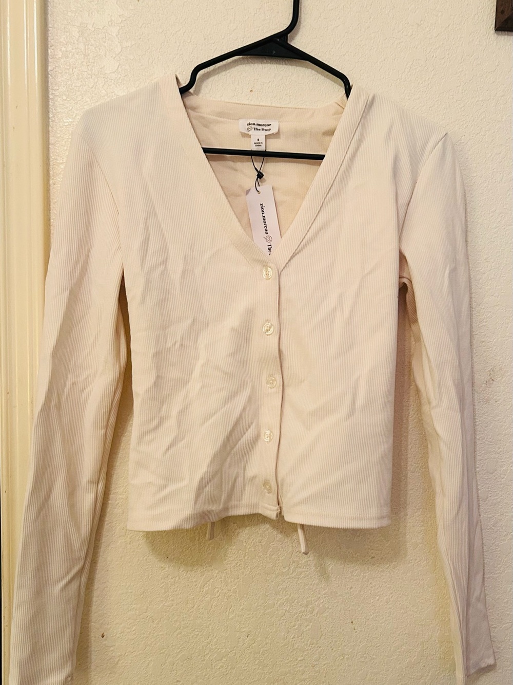 The drop Ivory V-Neck Button Front Rib cardigan tie on the back